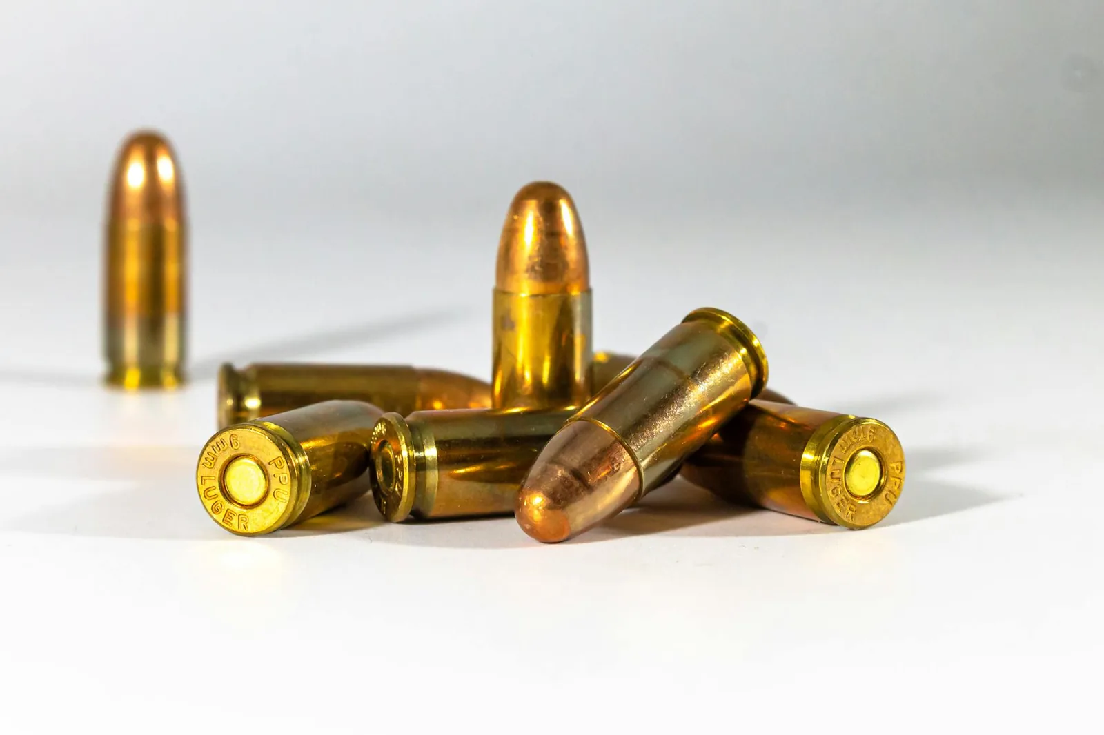Brass-cased pistol cartridges lined up on a white background.
