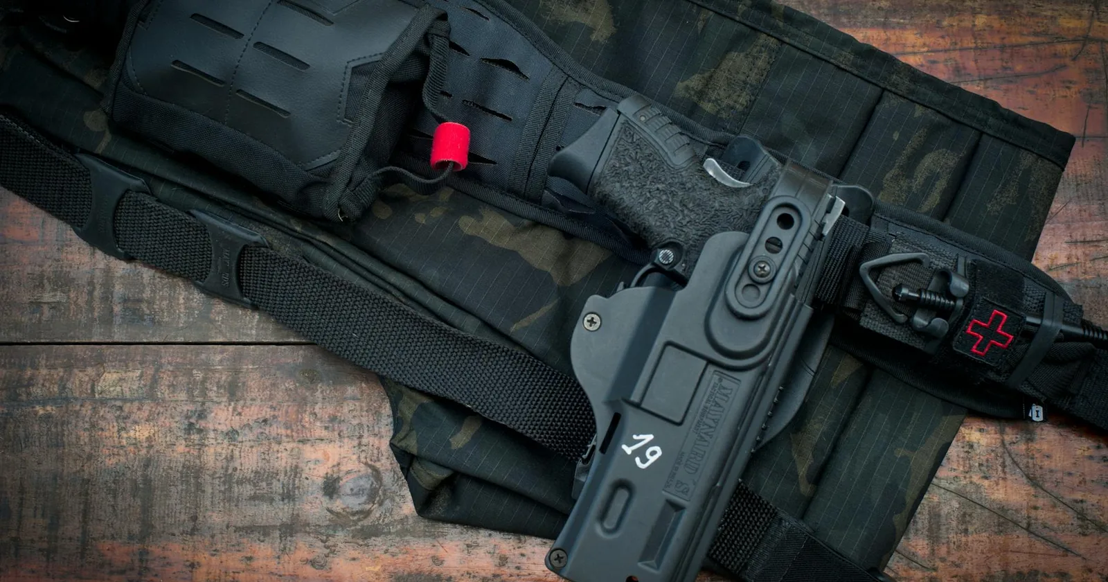 A compact handgun and a sturdy carry belt laid out on a wooden floor.