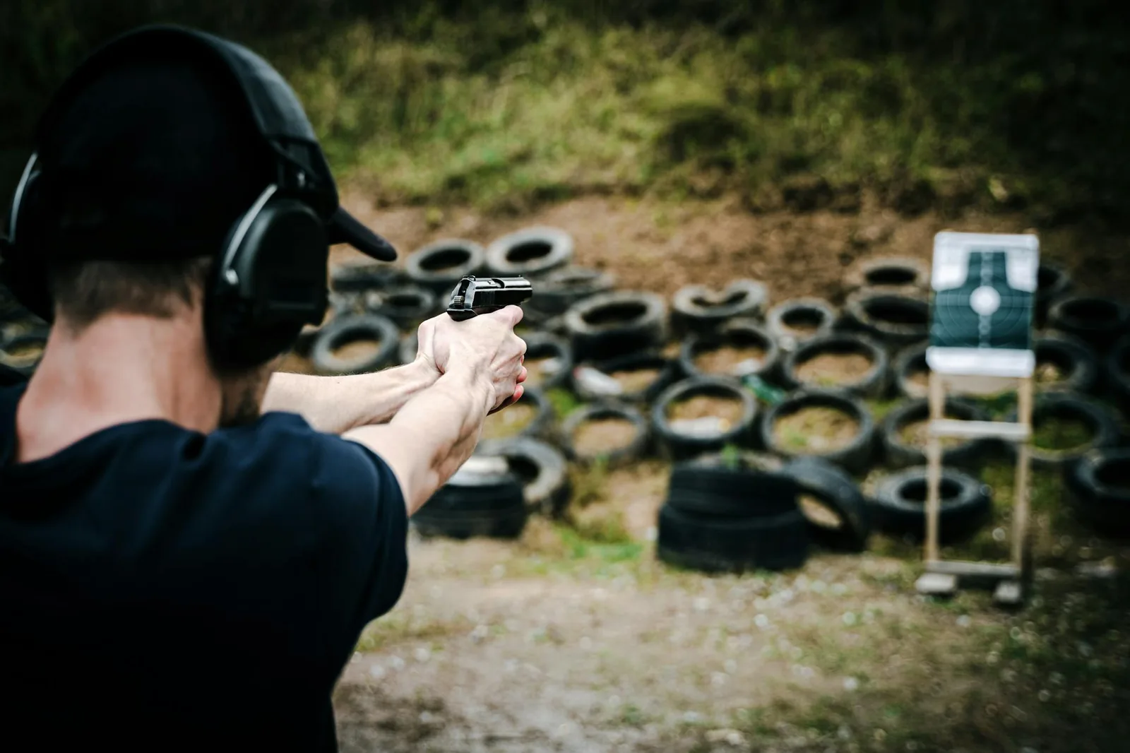 Adult student practicing pistol marksmanship at an outdoor shooting range.