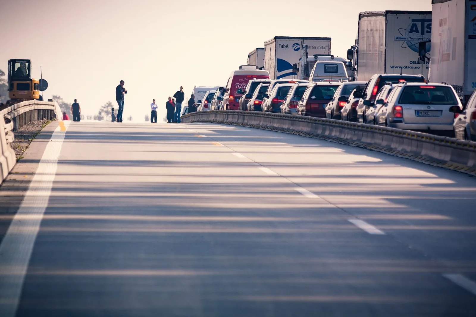 Cars and trucks in slow traffic on a multi-lane highway during the day.