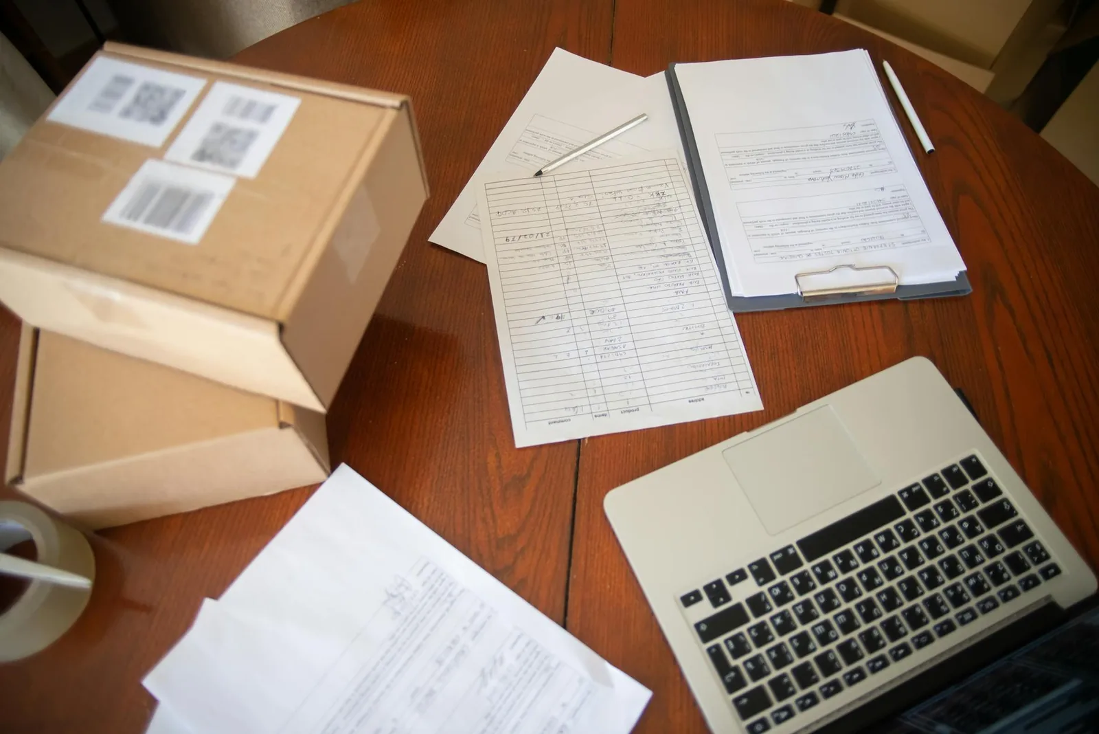 Paperwork and a laptop laid out on a wooden surface, illustrating the recordkeeping side of a firearm purchase.
