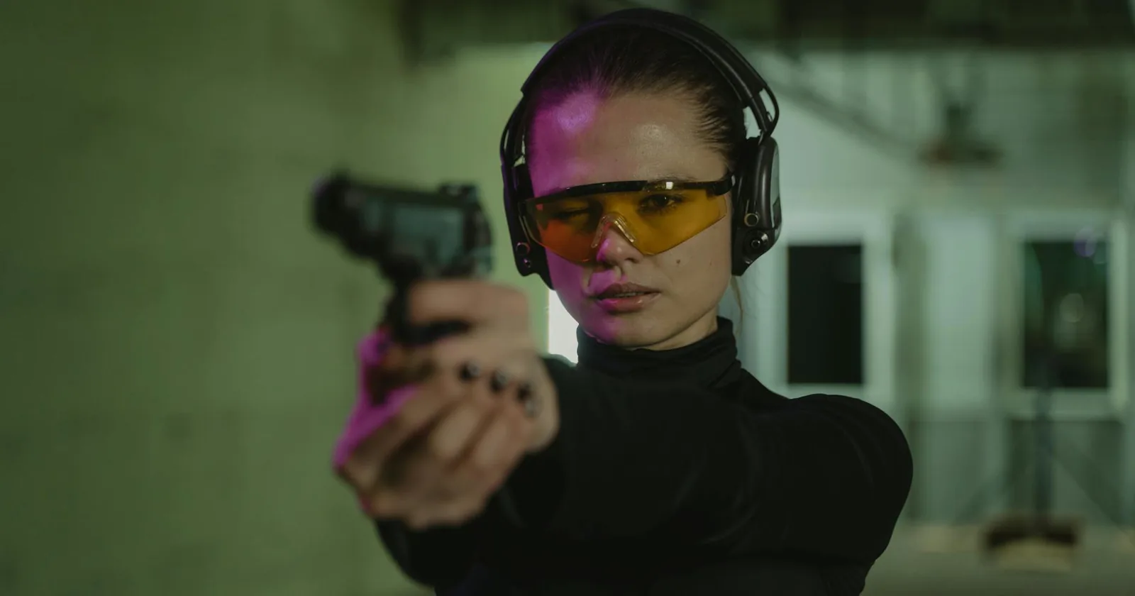 Student practicing pistol aim at an indoor range wearing eye and ear protection.
