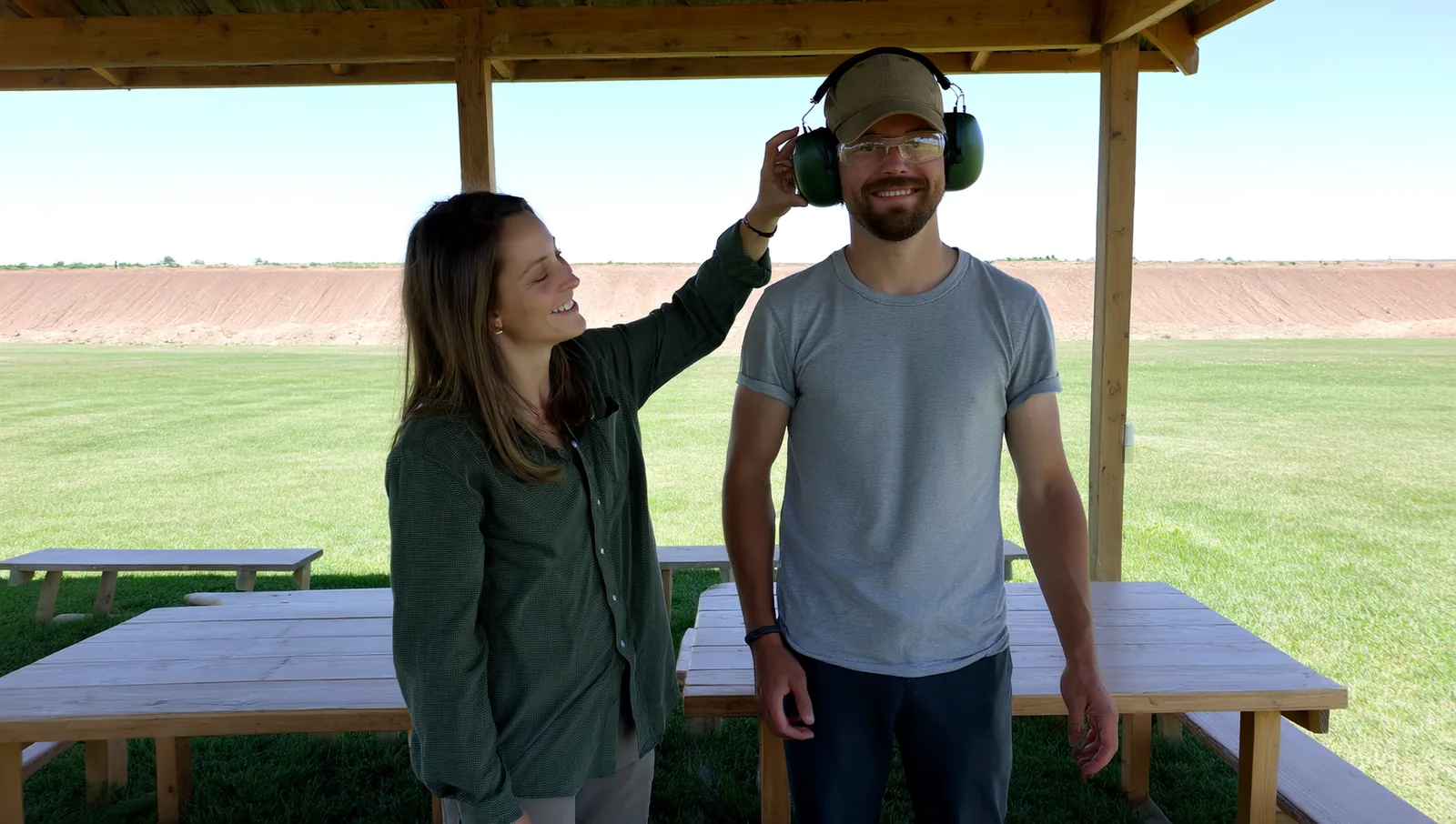 Woman fitting earmuffs on a friend at a range