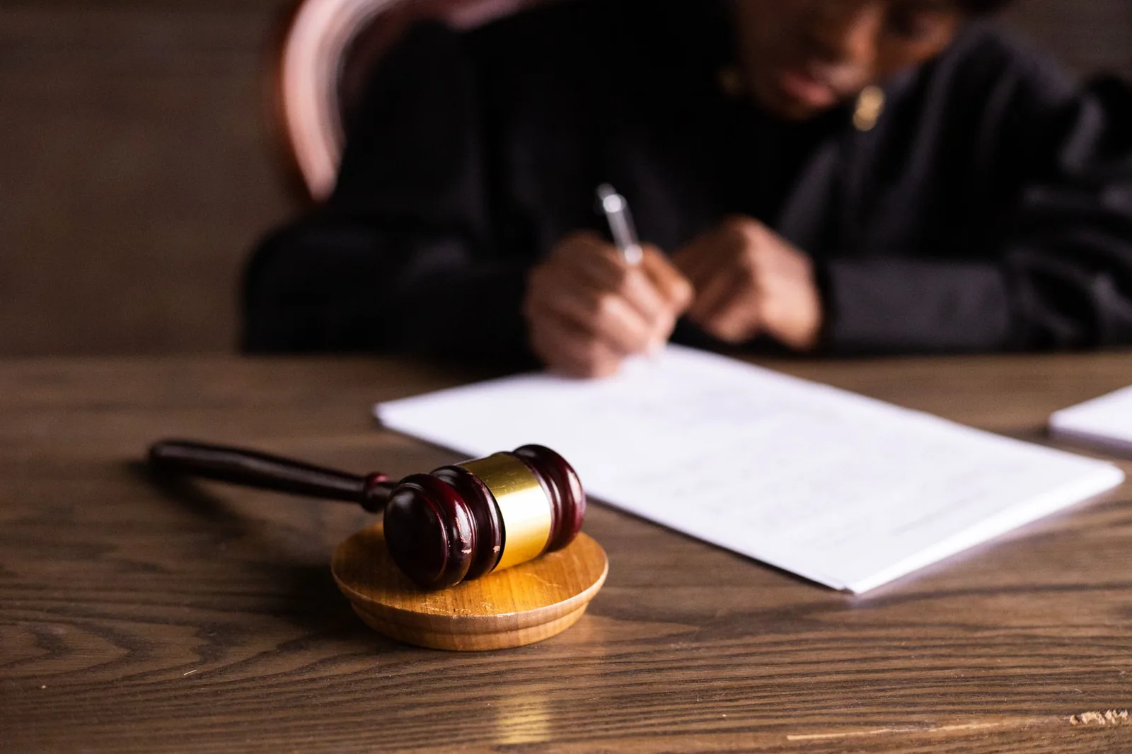 A gavel on a desk while a judge signs papers
