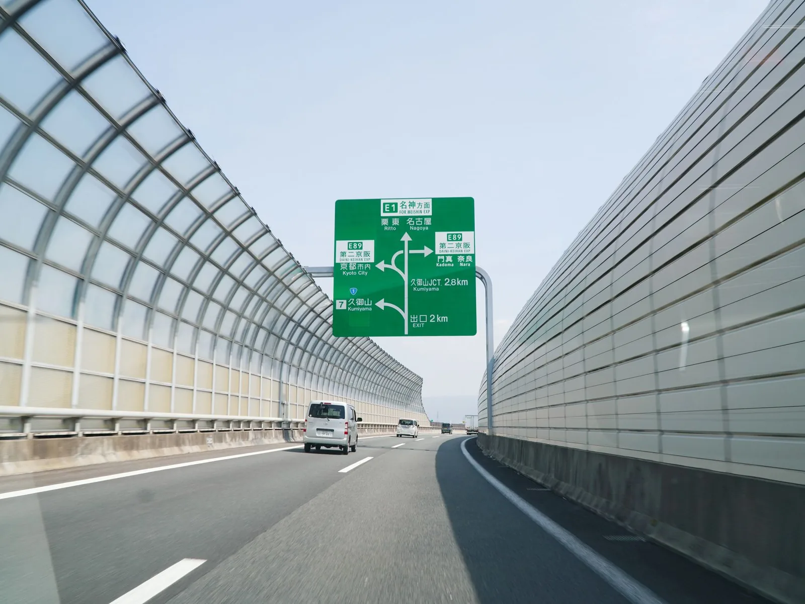 A wide highway with green directional signs and traffic, evoking interstate travel across state lines.