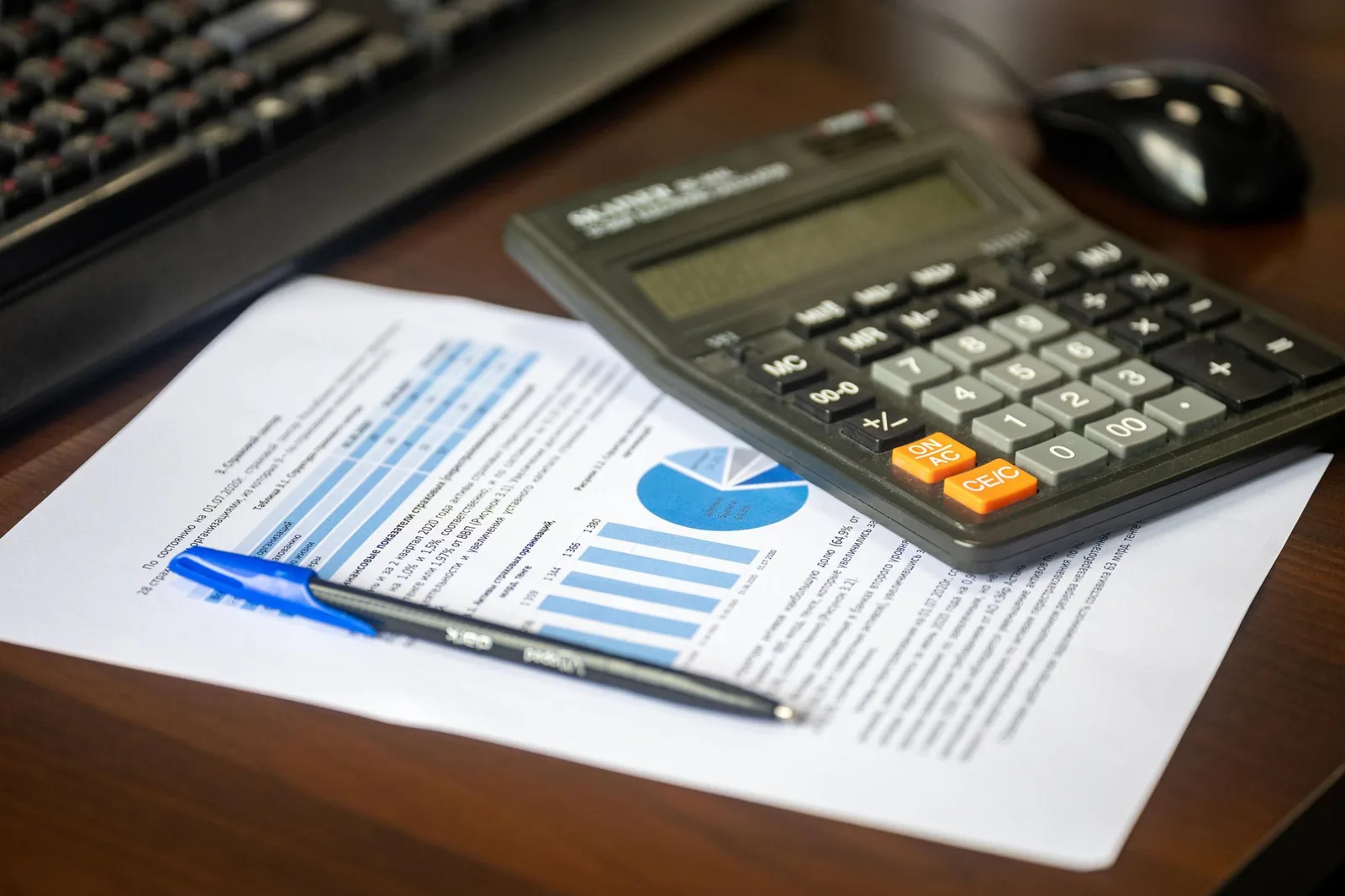 A calculator, pen and financial report laid out on a desk.