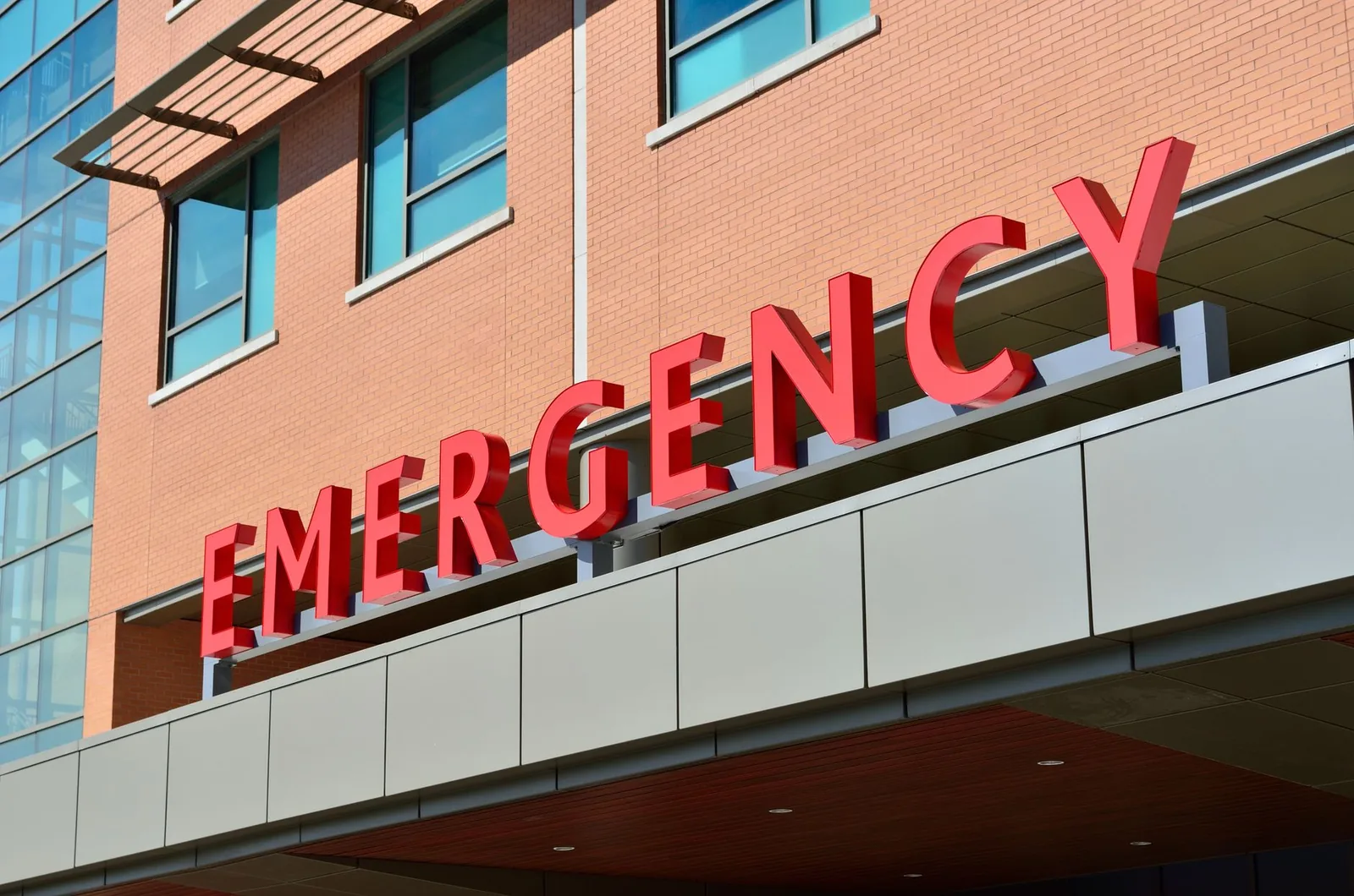 Red emergency sign above a hospital entrance canopy